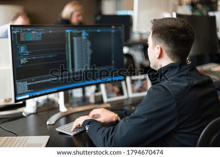 Male working on large screen with code