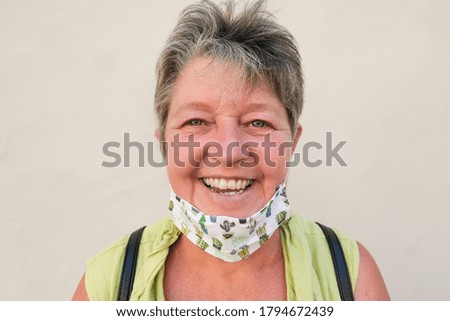 Happy woman with protective face mask - Portrait of senior woman laughing - Concept of coronavirus lifestyle