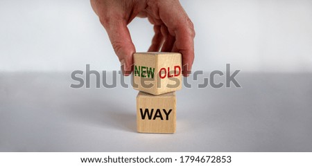 Male hand flips wood cube with 'new way' or 'old way' words on beautiful white background, mail hand. Copy space, business concept.