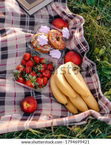 Healthy picnic for a summer vacation with freshly baked croissants, fresh fruit and fruit salad, sandwiches and a glass of refreshing orange juice laid out on a red and white checked cloth and hamper.
