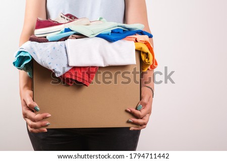Woman holding a donate box. Donation box for giving. Sharity social activity. Cardboard box with clothes for charity. Female volunteer holding donations. Case full of clothing for giving. Help poor. Royalty-Free Stock Photo #1794711442