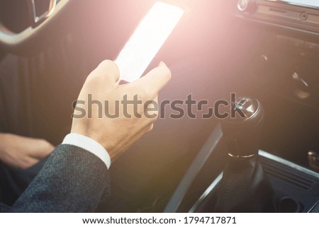 businessman holding a phone in his hand the car