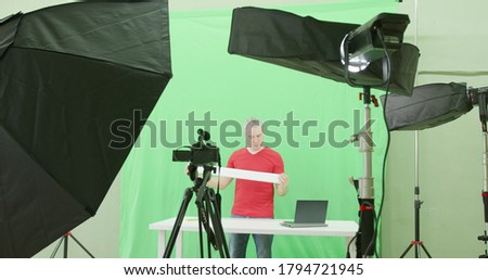 Blogger records a review video clip for social network on green screen background in the studio