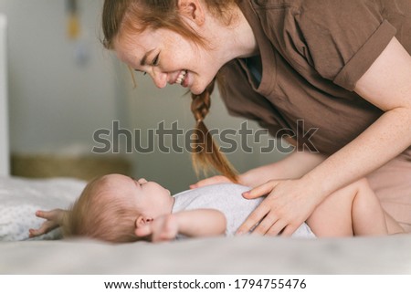 Mom hugs with her newborn baby in bed. Nine month old baby. Baby care, tenderness, motherhood