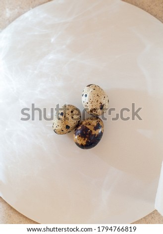 Three quail eggs are laying on the board, ready to be cooked, crease of the light