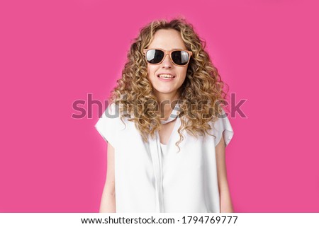 Young woman wearing glasses smiling shrugging shoulders. Female portrait. Isolated on pink background