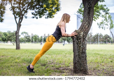young woman doing standing push-ups in the park