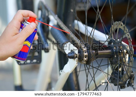 hand holding spray lubricant in his hand to lubricate the bike chain