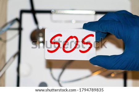 White lightbox with word SOS abbreviation of save our soul ship or sibling over shoulder on wood background