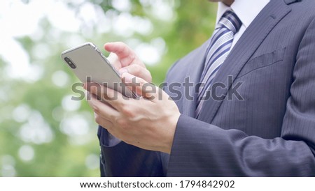Businessman is using smartphone outside