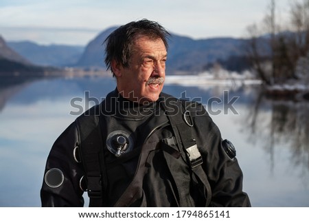 Mature Diver in a Drysuit After a Rescue Dive in a Freezing Cold Lake