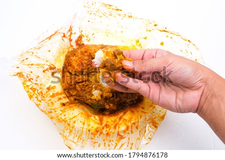 A picture of hand taking "nasi kandar ketagih" before put in the mouth on isolated white background. Famous Northern Malaysia food, rice eat with mix curry, chicken or beef and vegetables.