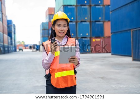 Container worker women in cargo shipping workplace working and checking with laptop at cargo container shipping.