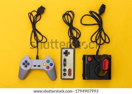 Wired retro gamepads and joystick with wound cable on yellow background. Video game, gaming. Top view
