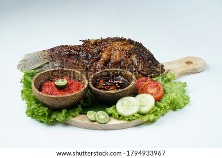 photos of food products, View from above Close up of grilled fish or grilled gouramy with chili sauce and vegetables on a textured wooden table. Usually used for menu list pictures or food pictures in
