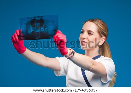 Girl doctor in medical clothes on hands wearing medical gloves. The girl a medical worker holds a roentgenogram in her hands, she looks at the picture.