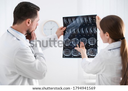 Professional orthopedist and his colleague examining X-ray picture in office