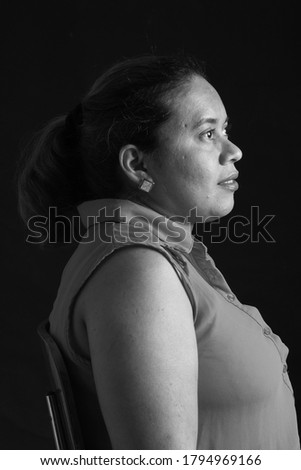 portrait of a woman sitting on chair look side on black background,