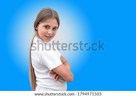Portrait of cute attractive girl with long hair smiling while standing on blue background