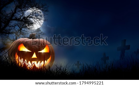 A spooky halloween pumpkin, Jack O Lantern, with an evil face and eyes on the grass in a graveyard with a misty night sky background with a full moon. Royalty-Free Stock Photo #1794995221