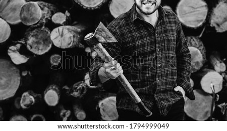Portrait of a bearded brutal woodcutter holding ax in hand