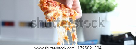 Hand takes a piece of hot pizza from the box. Order products with delivery to the office or home