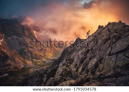 Silhouette of active hiker running in mountains. Orange landscape in background. Edit space, sport photo hilly landscape