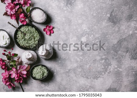 Set of natural skin care products and pink flowers on a grey background. Flat lay, top view, copy space.