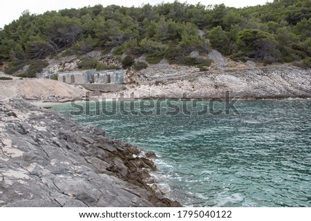 Hidden cove beach on the island of Brac, Croatia. Rocky shore with forest trees surrounding the small paradise. Area in front of the hidden bunker belonging to Yugoslavian leader Tito