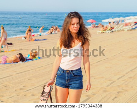 A beautiful young woman in shorts walks on the morning sandy beach on the Costa Brava, Spain, holiday season