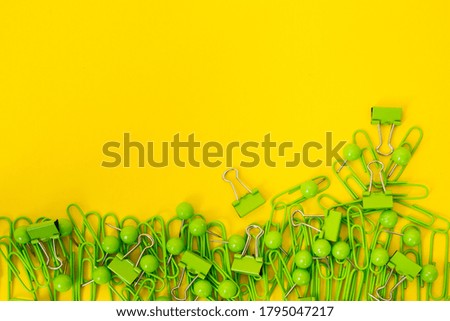 paper clips, pins and binders on yellow background