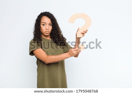 young black woman sad, depressed, unhappy, holding the $ symbol to form a word or a sentence.