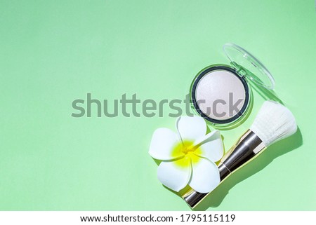 Makeup brush and powder on a green background. Cosmetics and fashion concept. Hard light. Flat lay, copy space
