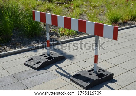 entrance barrier protection of entry of persons stops transporting cars into the object path raod red white stripes sign 