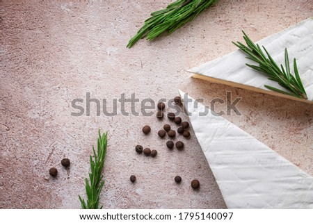 Blue cheese (brie) on a beige concrete background with rosemary, allspice close-up in a high key horizontal