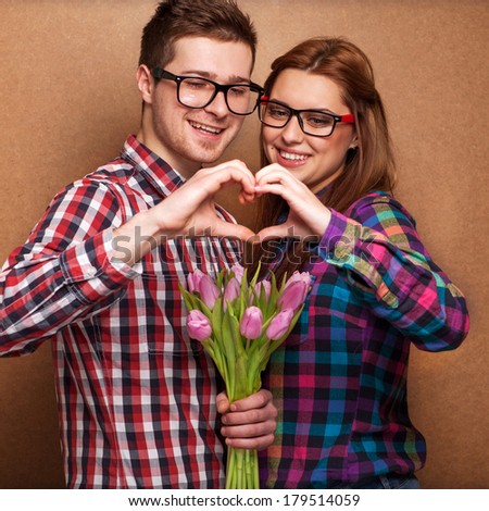 Young couple in love make a heart and hands are holding a bouquet of tulips. The concept of Valentine's Day 