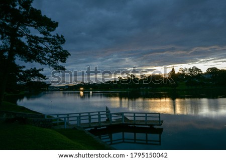 sunrise on the lake with reflection of the lonely bridge and dramatic sky