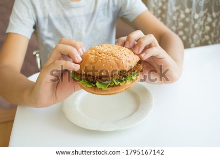 Boy holding a Burger in hands. The concept of fast food. Tasty unhealthy Burger sandwich in hands, ready to eat