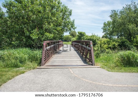 Eola Community Park bridge crossing in the natural reserve with greenery on a sunny day in Aurora, Illinois