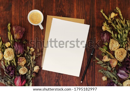 Paper card mockup with envelope and coffee on wooden table with dried flowers