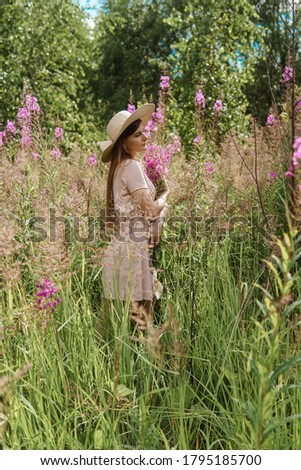 young woman in nature with a bouquet of pink wild flowers. A bouquet of Ivan-tea in the hands of a woman.