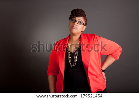Plus size black woman wearing glasses in a smart business outfit on a neutral grey background