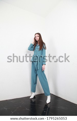 European belarusian model wearing navy blue summer suit posing in the studio with white walls for a catalog photosession of clothes for online store, promoting new brand and trends