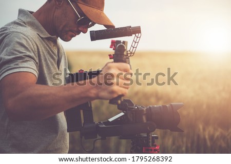 Caucasian Men Professional Camera Operator Taking Video Shot Using DSLR Modern Digital Camera and Gimbal Stabilizator For Steady Footage. Videography Theme.