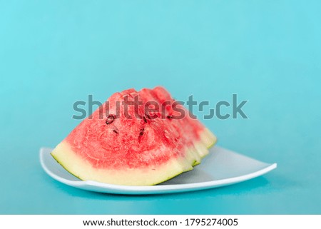 Water melon slices on a plate on blue background. Juicy fresh tasty summer dessert. Stock photo
