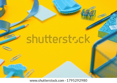 Minimalism, Back to school concept, blue school supplies on yellow background, with copy space