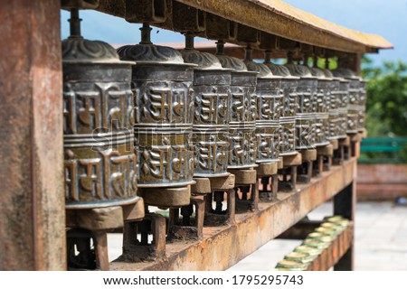 Picture of prayer wheels in a row. Buddhist praying drums with mantra Om Mani Padme Hum writen on it.