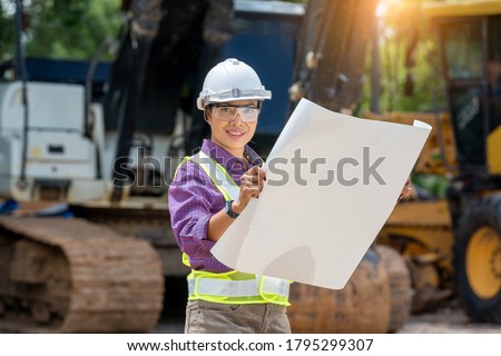 Engineer or architect women holding blueprints with loader truck at construction site,Engineering construction car vehicle at the work area.