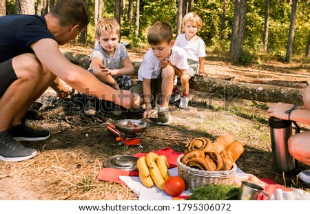boys cooking on campfire With mother and father on camping.hiking in the forest, family weekend in summer.