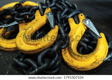Iron chains with hooks lie on the floor of the workshop. A device for loading and unloading goods. Royalty-Free Stock Photo #1795307104
